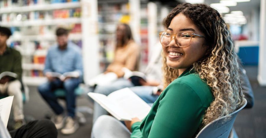 A smiling student studying with others in a library