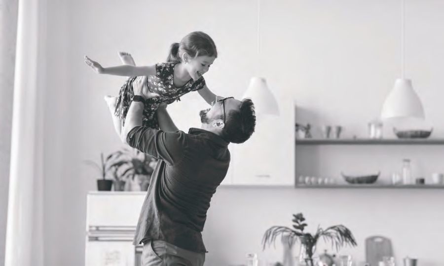 A father playfully lifting his young child at home