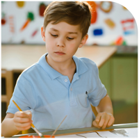 A young boy concentrating on a craft activity at a table.