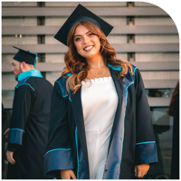 A young woman in a graduation gown and cap, smiling proudly.